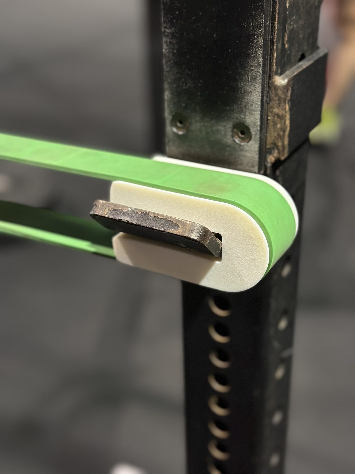 HookHuggers in use — pair of PETG J-hook sleeves with a green resistance band loaded across them on a CrossFit rig